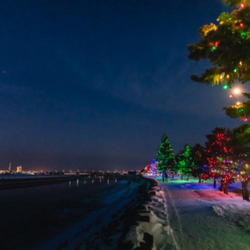 View of city lights and christmas lights across the river at night