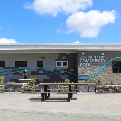 The grey brick exterior of an outdoor community pool on a sunny day