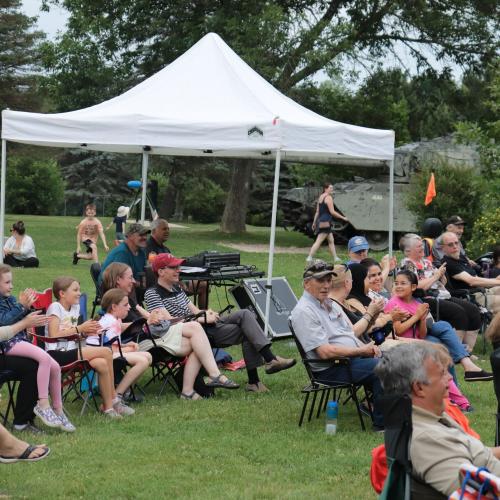 A crowd sitting in a park in camping chairs