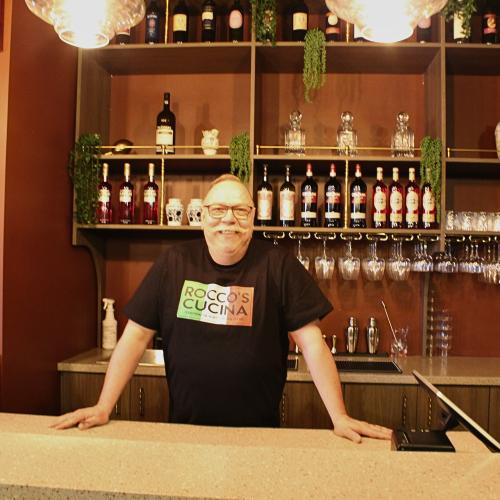 Man smiling behind a restaurant bar