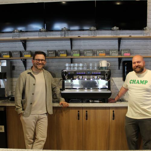 Two men smiling by barista counter