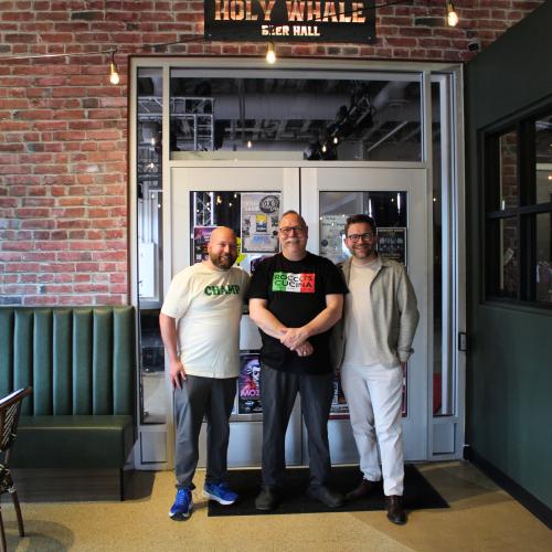 Three men standing at the door of a business smiling