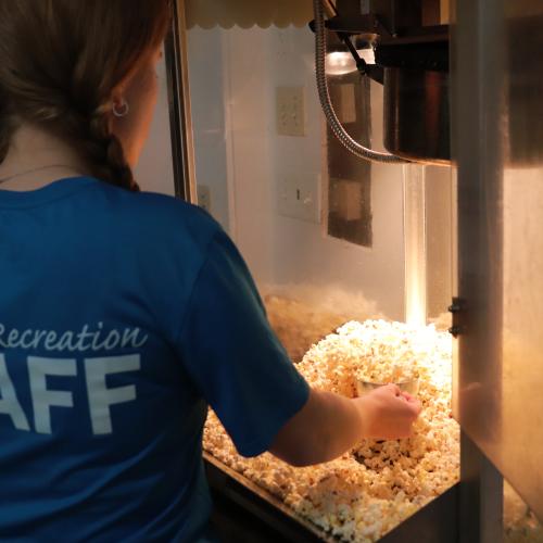 A staff member scooping popcorn 