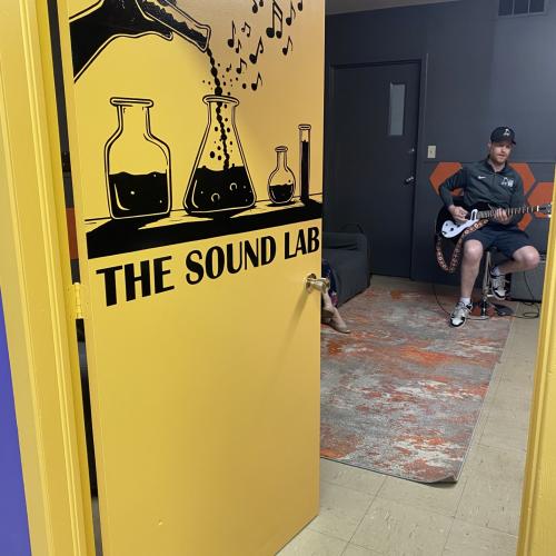 A yellow door opening with a man playing guitar inside