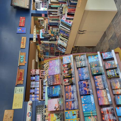 Bookshelves with a blue wall in the background. The blue wall has wooden signs with sayings displayed.