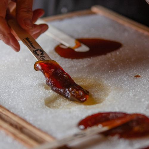 Someone dipping popsicle stick in maple taffy on the snow