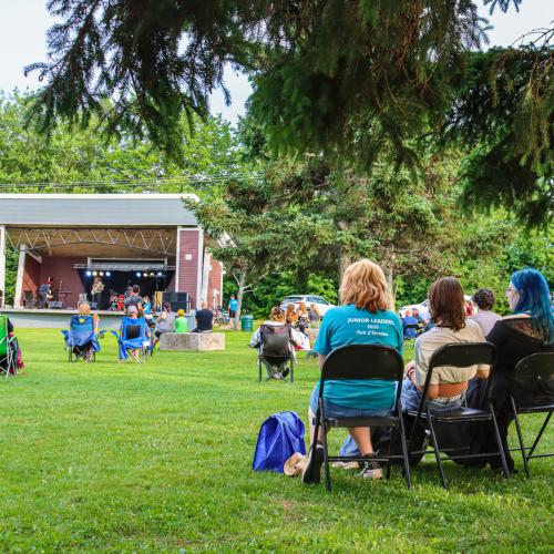 people sitting on chairs watching music on the outdoor bandstand