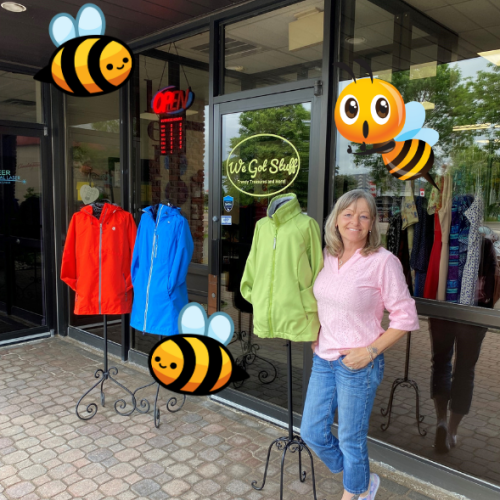 Owner in front of We Got Stuff shop surrounded by cute bee graphics.