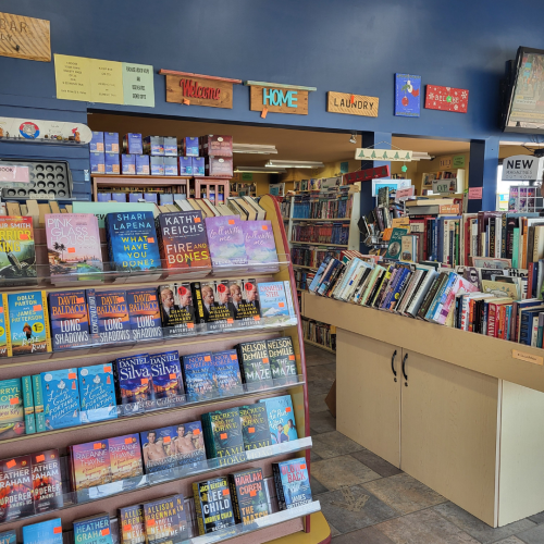 Bookshelves with a blue wall in the background. The blue wall has wooden signs with sayings displayed.
