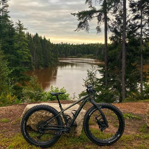 A black bike placed against a stone Infront of the Mill Creek Lookout Point (Body of water).