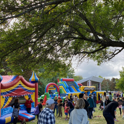 A crowd of people in a park with bouncy castles