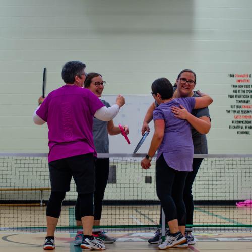 Two teams hugging over pickleball net