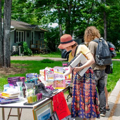 People outside browsing yard sale items on a table