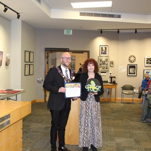 Artist holding artwork with mayor, smiling
