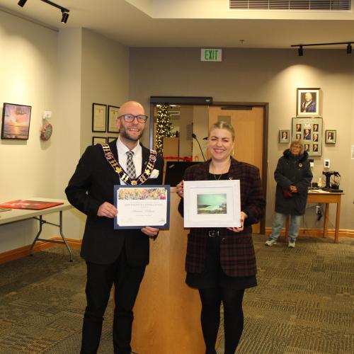 Woman holding artwork with mayor, smiling