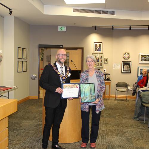 Artist holding artwork with mayor, smiling