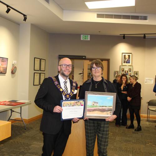 Artist holding artwork with mayor, smiling
