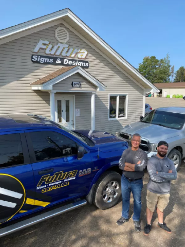 Futura Signs owner and son standing outside building smiling
