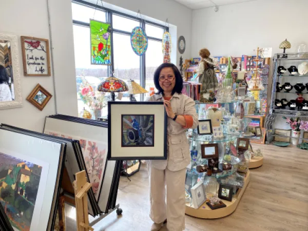 Owner of custom framing store smiling holding a framed photo