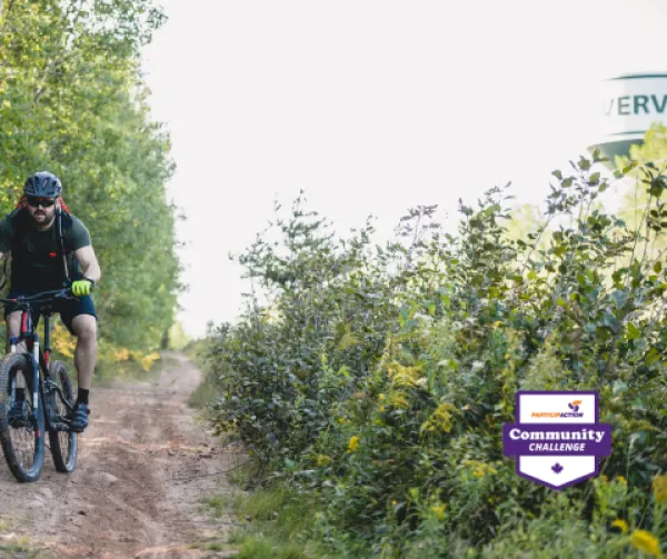 Mountain biker on a dirt trail surrouned by bushes and trees