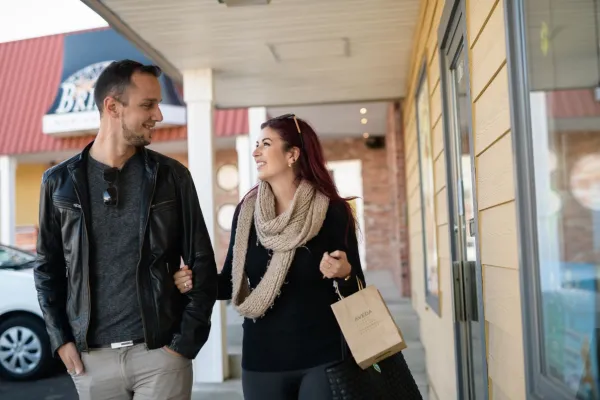 A man and woman walking past shops. 