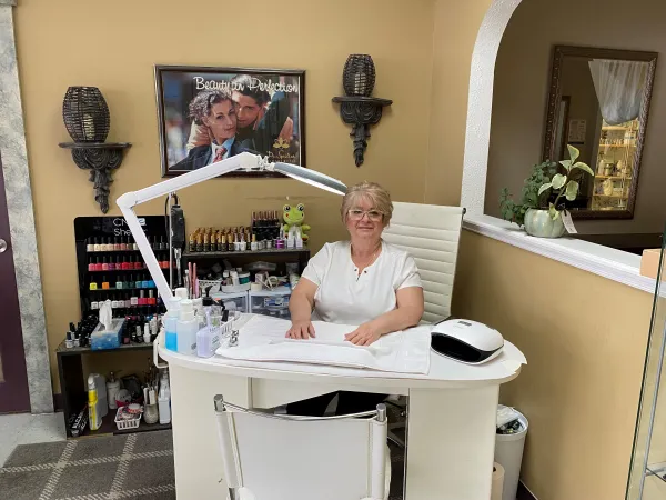 Sylvia Furlaga sits behind a nail station