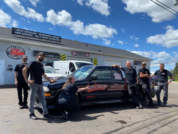 Tony and staff standing outside of Dents & Stones Automotive next to a vehicle