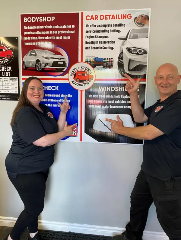Tony and staff pointing to their services sign