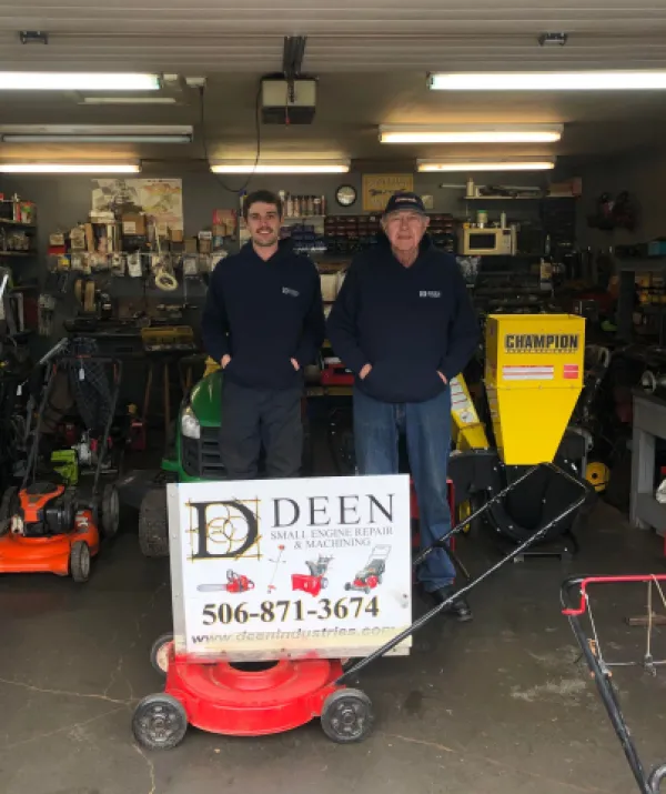 Two men standing inside small engine repair shop