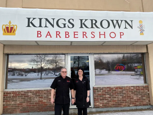 Owners stand outside barbershop