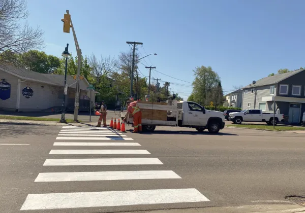 A Riverview truck and two staff line painting a crosswalk 