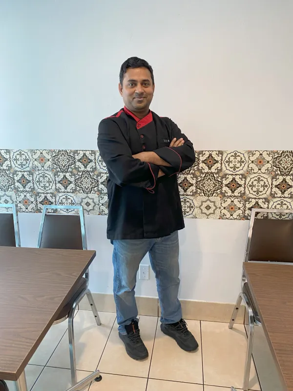 Restaurant owner smiling in store with arms crossed