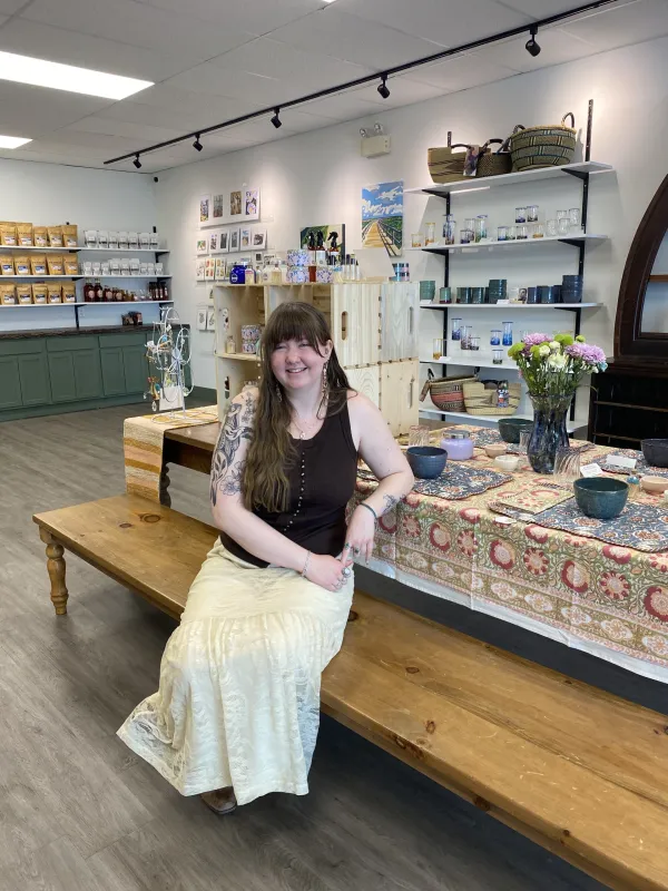 Fine craft store owner sitting at a display table, smiling