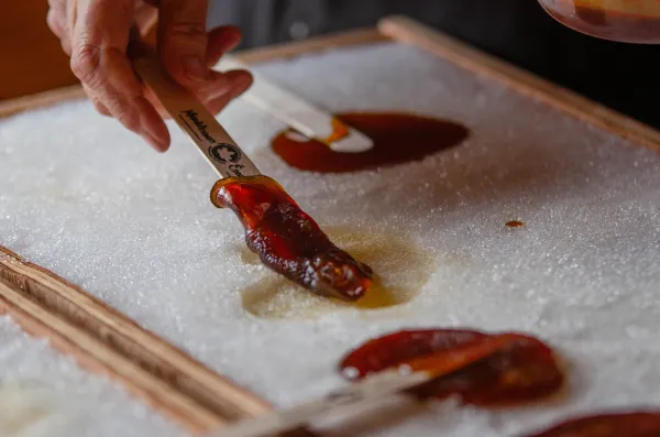 Someone dipping popsicle stick in maple taffy on the snow