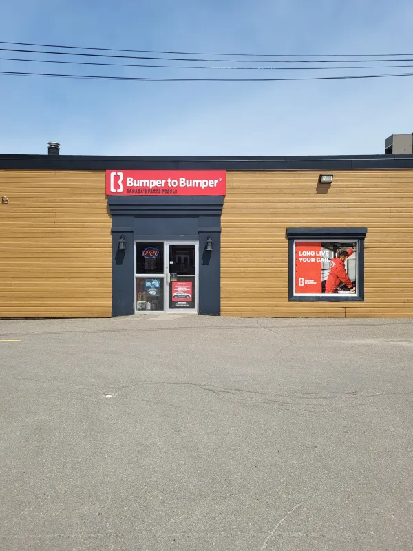 Bumper to Bumper store front- Brown building with red branded signs.