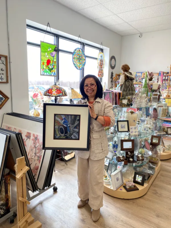 Business owner holding a frame. Giftware in the background