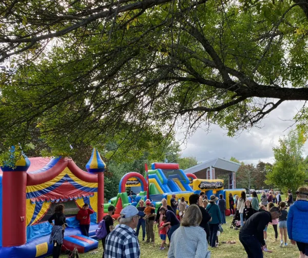 A crowd of people in a park with bouncy castles