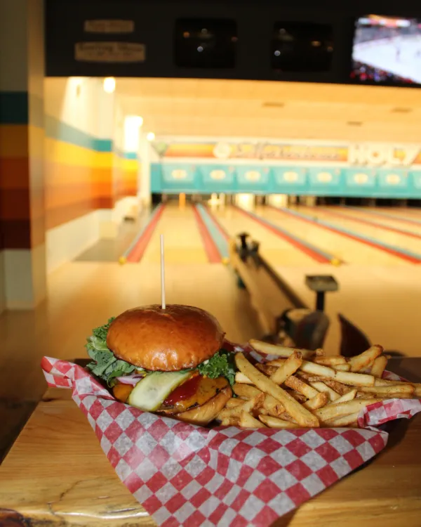 Burger and fries on a platter with a bowling lane in the background