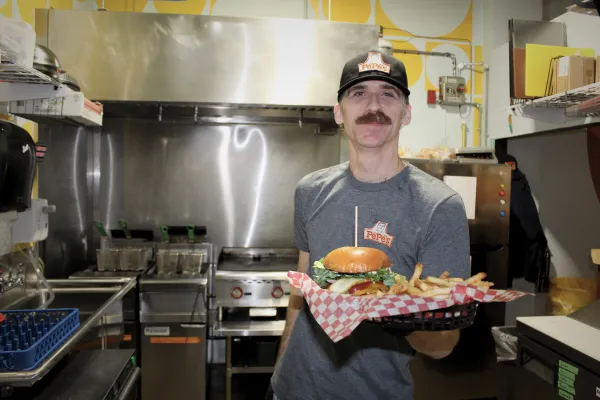 Chef holding a platter with a burger & fries in his kitchen