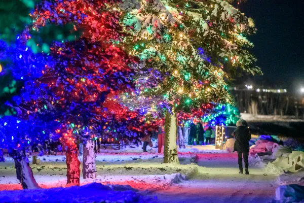 Family walking along the Riverview waterfront, which is decorated with festive holiday lights.