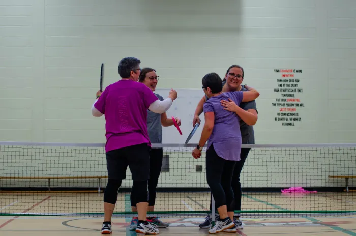 Two teams hugging over pickleball net