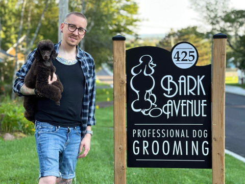 Stephen next to the Bark Ave store sign holding a dog