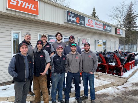 9 male team members stand outside cr yardworks and equipment in winter