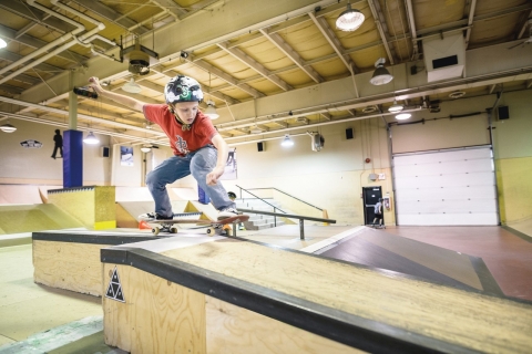 Young person wearing a helmet while riding down an indoor skateboard ramp