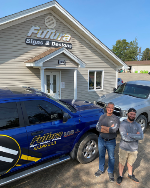 Futura Signs owner and son standing outside building smiling
