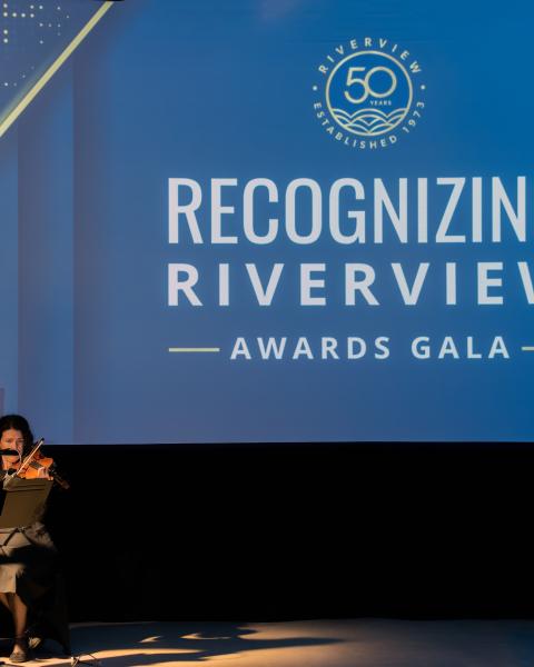 Harp and violin musicians play in front of recognizing riverview backdrop