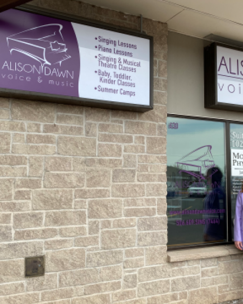 Owner of Alison Dawn voice and music standing and smiling outside storefront