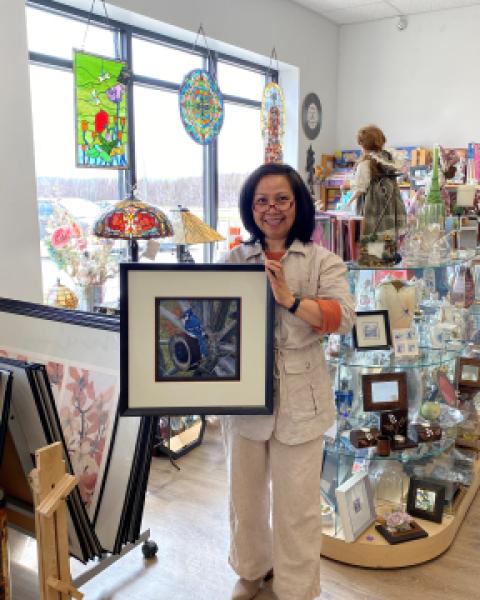 Owner of custom framing store smiling holding a framed photo