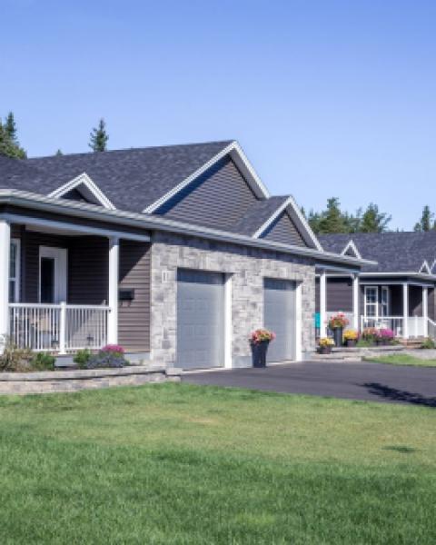 A row of semi-attached housing with green lawn and blue sky