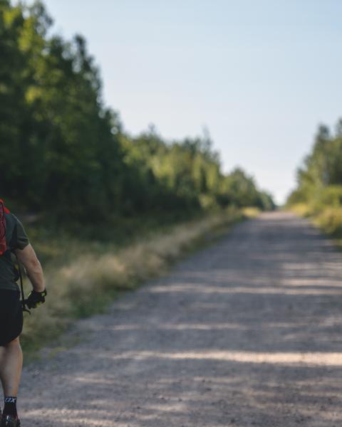 man biking on gravel trail with red bookbag